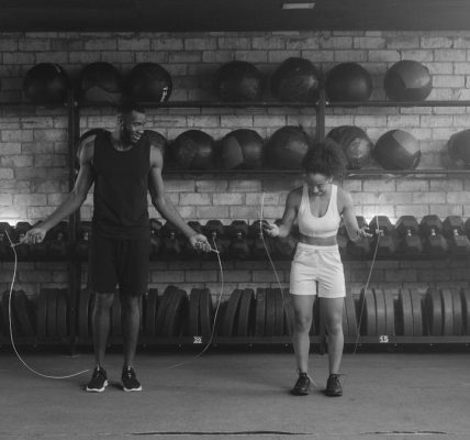 A fit couple working out in the gym with jump ropes, promoting a healthy lifestyle.