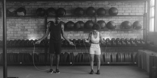 A fit couple working out in the gym with jump ropes, promoting a healthy lifestyle.